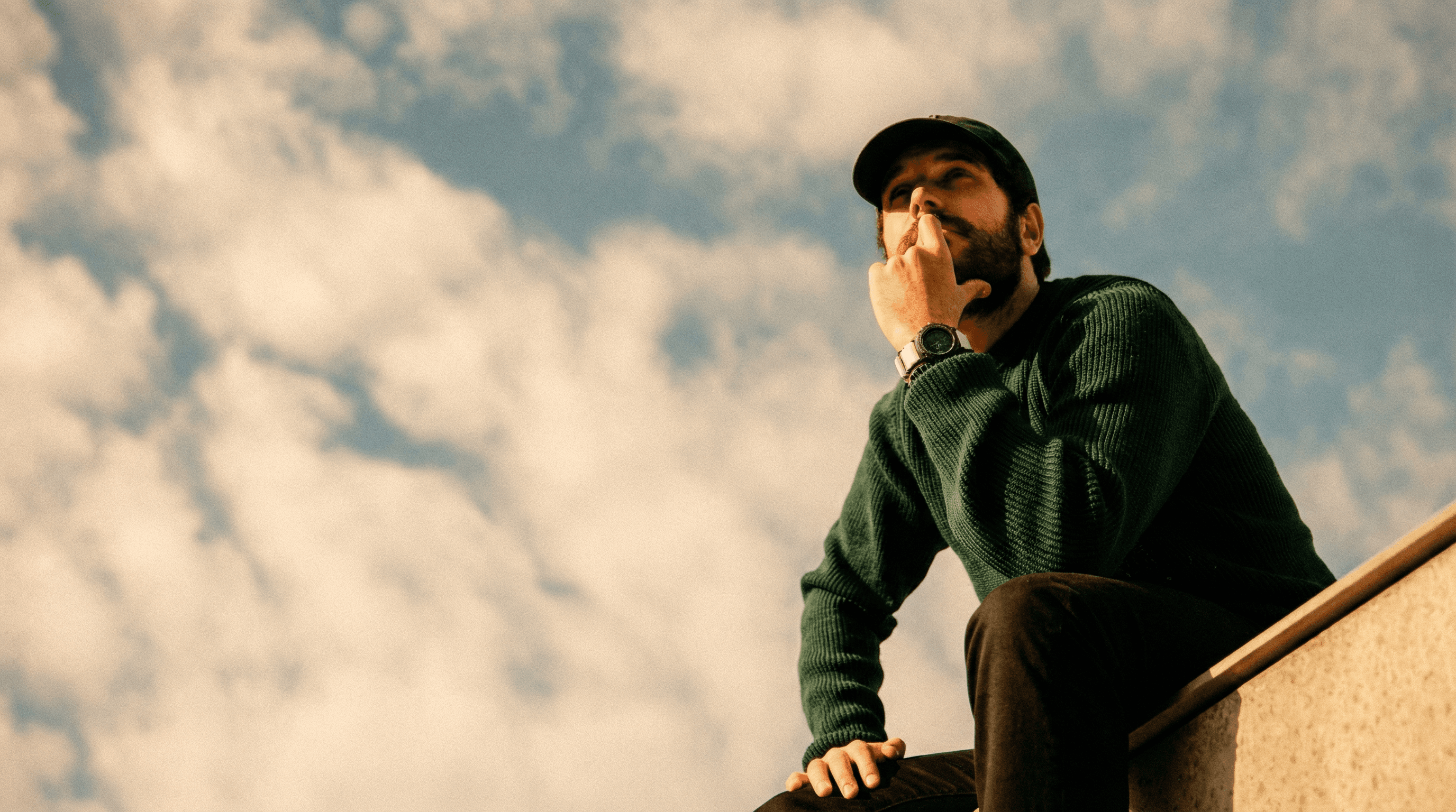 Man sitting contemplatively, looking up at the sky